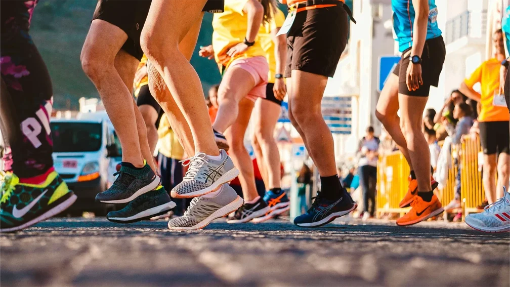 Participants à une course de rue portant des baskets de sport, en pleine action lors d’un marathon urbain.
